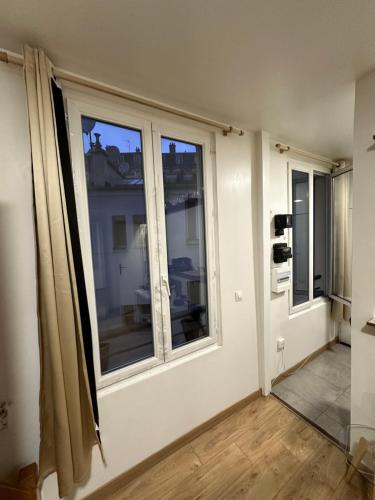 Zimmer mit zwei großen Fenstern in einem Zimmer in der Unterkunft Studio equipé, lumineux a Paris in Paris