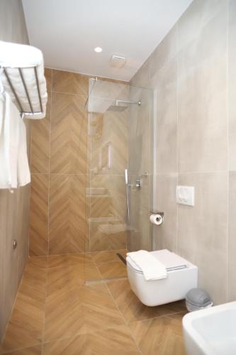 a bathroom with a toilet and a glass shower at J&D Rooms Korce in Korçë