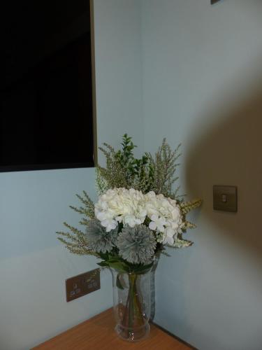 a vase filled with white flowers sitting on a table at Hamilton Court Hotel Hoole in Chester