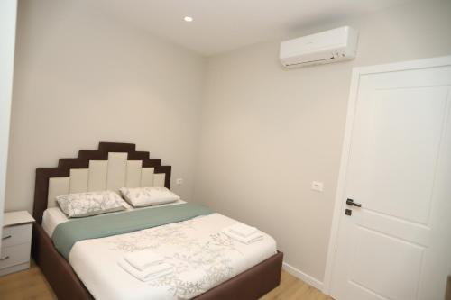 a small bedroom with a bed and a white wall at J&D Rooms Korce in Korçë