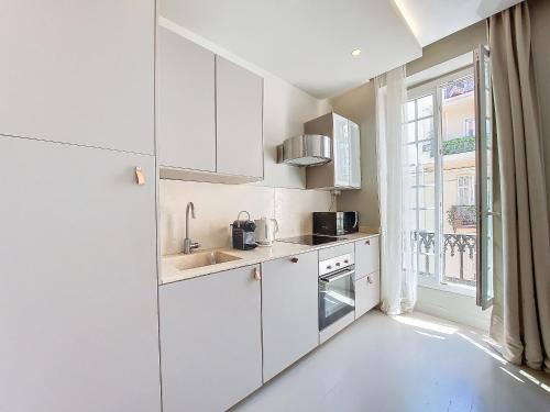 une cuisine blanche avec des armoires blanches et une fenêtre dans l'établissement Nestor&Jeeves - COEUR DAZUR - Central - Modern, à Nice