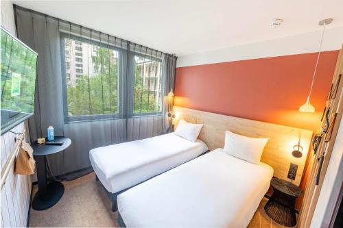 2 łóżka w małym pokoju z oknem w obiekcie ibis Styles Paris 16 Boulogne w Paryżu