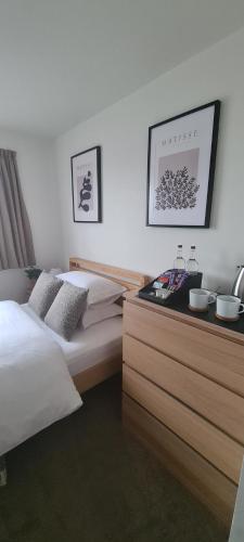 a bedroom with a bed and a wooden dresser at Carolines rooms in Cherry Hinton