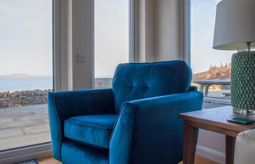 a blue chair sitting in a room with a window at Solas Alainn in Staffin