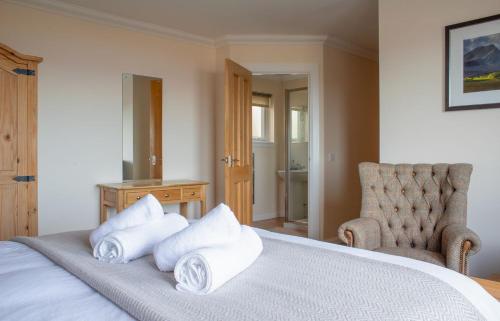 a bedroom with a bed with pillows and a chair at Solas Alainn in Staffin