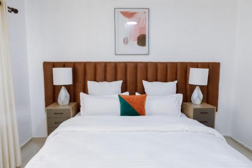 a bedroom with a large bed with two lamps at Epignosis Apartments in Lusaka