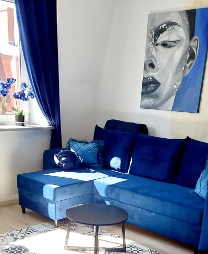 a blue couch in a living room with a table at Gold Apartament in Wałbrzych