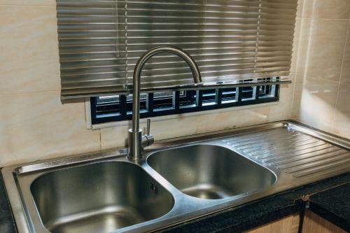 a stainless steel sink in a kitchen with a window at Epignosis Apartments in Lusaka