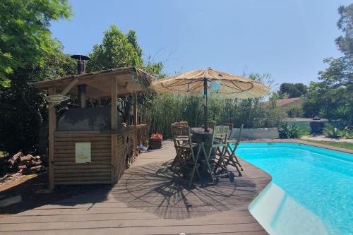 a bar with an umbrella next to a swimming pool at LE CABANON Piscine Jacuzzi Sauna Paillote in La Seyne-sur-Mer