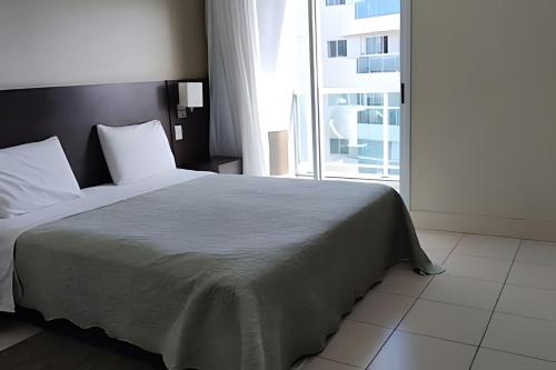 a bedroom with a large bed with a large window at Studio pé na areia, vista, internet e ar in Macaé