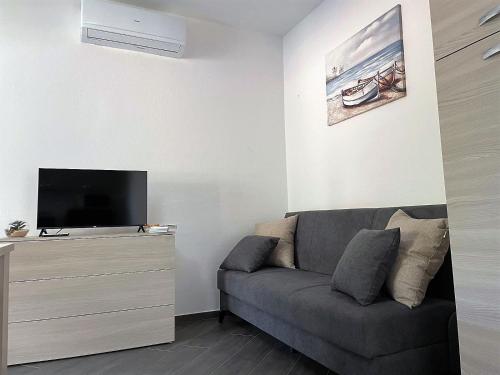 sala de estar con sofá y TV de pantalla plana en Endless Summer Apartment en Olbia