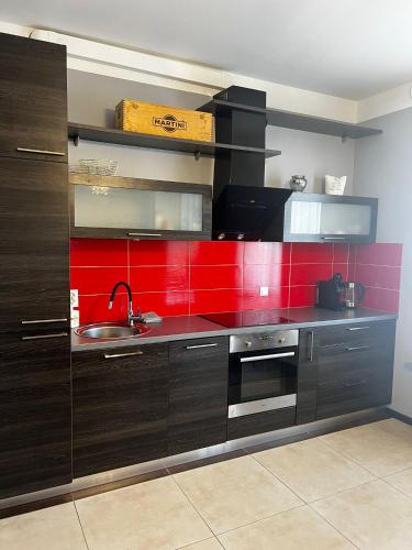 eine Küche mit einem Waschbecken und einer roten Wand in der Unterkunft LK Apartment in Mārupe