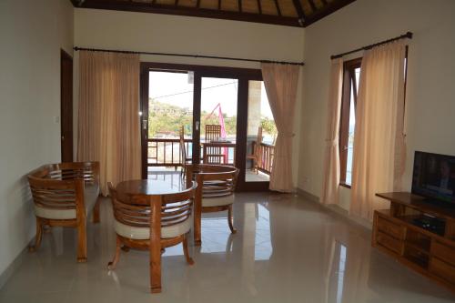 a dining room with a table and chairs and a television at Shankara Parada Villas in Amed