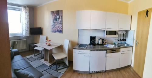 ベーレンシュタインにあるFerienwohnung Hutweideの白いキャビネット、テーブル、ソファ付きのキッチンが備わります。
