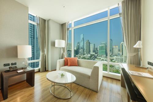 a living room with a couch and a large window at Eastin Grand Hotel Sathorn in Bangkok
