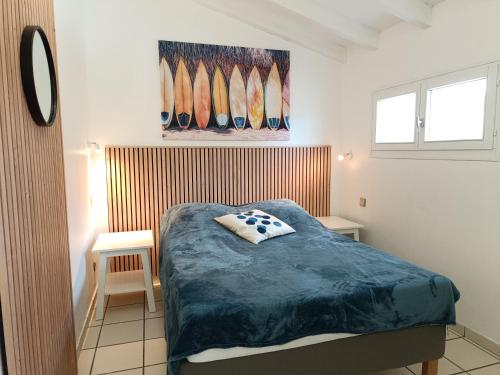 a bedroom with a bed and a picture of surfboards at T2 climatisé à 2 minutes de la plage du Pont Tournant - 4BRANR in Saint Cyprien Plage