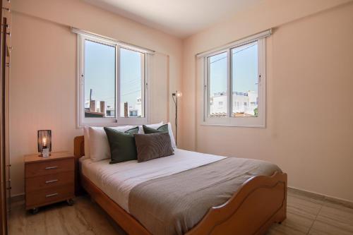 a bedroom with a bed and two windows at Phaedrus Living: Universal City Flat Alina in Paphos City