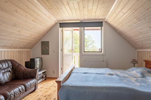 um quarto com uma cama, um sofá e uma televisão em Holiday accommodation with great nature experience near Laholm em Knäred