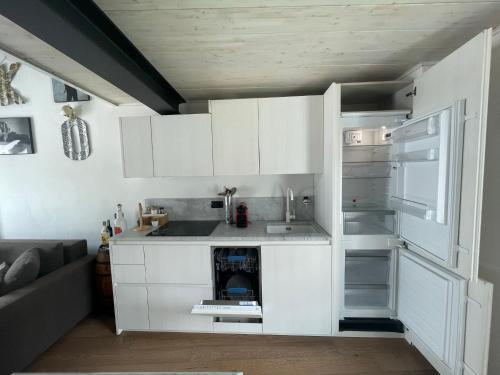 uma cozinha com armários brancos e um frigorífico aberto em Casa P em Malgrate