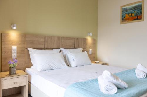 a bedroom with a large white bed with towels on it at Angeliki Beach Hotel in Megali Ammos