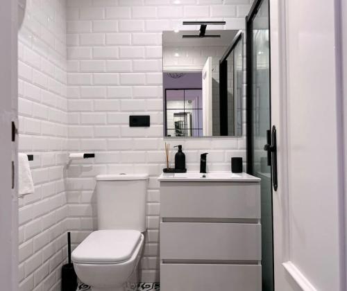 a white bathroom with a toilet and a sink at El Solsticio - 30601 in Somo