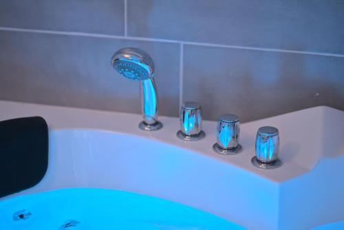 une salle de bain avec un sèche-cheveux dans une baignoire avec des lumières bleues dans l'établissement Bliss Insolite Jacuzzi Parking Free 5min du Centre, à Mulhouse