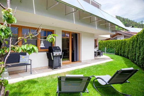 a yard with two chairs and a trash can at Mosers Ferienwohnung am Sonnenhang in Jenbach