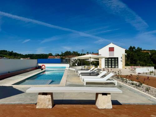 a group of white lounge chairs sitting around a swimming pool at Casa do Pátio, casaspensadas in Juncal