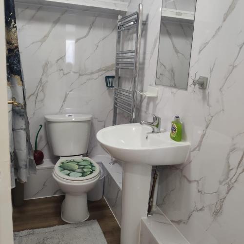 a white bathroom with a toilet and a sink at Captivating 3-Bed Apartment in Romford in Romford