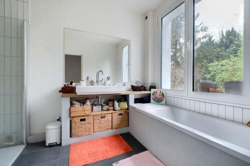 une salle de bain avec une baignoire, un lavabo et une fenêtre dans l'établissement Maison proche village olympique, à Saint-Denis