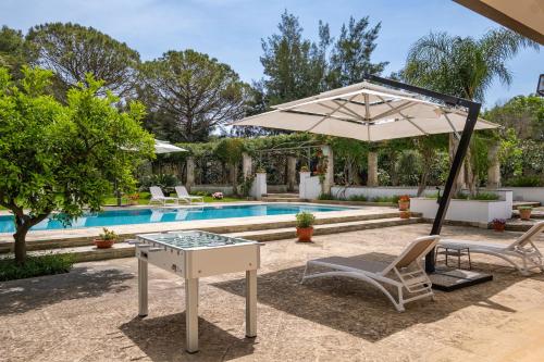 an umbrella and a table and chairs next to a pool at Tenuta Il Carretto in Monteroni di Lecce