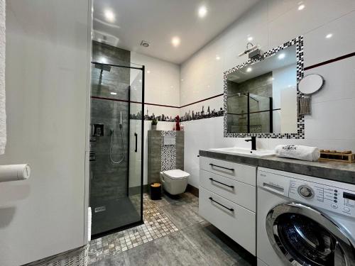 a bathroom with a shower and a washing machine at Apartament Ezuka - Twoje miejsce na mazurach in Giżycko