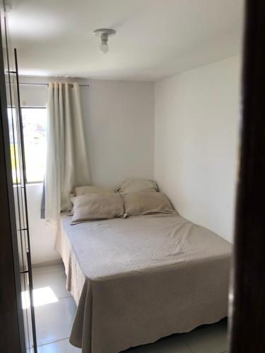 Bett in einem weißen Zimmer mit Fenster in der Unterkunft Apartamento para São João in Campina Grande