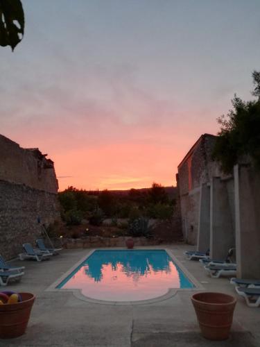 une piscine avec un coucher de soleil en arrière-plan dans l'établissement Domaine de La Pierre Chaude, à Portel-des-Corbières