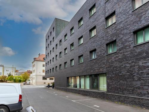 B&B HOTEL Fulda-Hbf في فولدا: مبنى من الطوب الأسود مع فان أبيض متوقف في الأمام