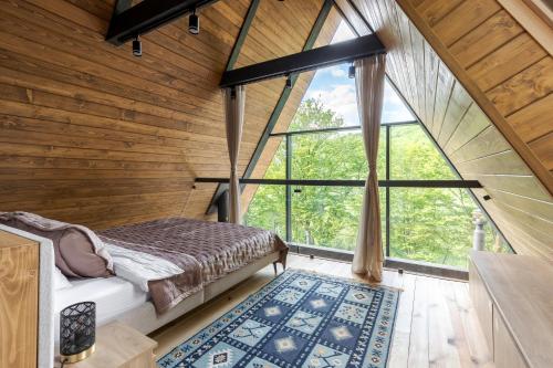 - une chambre dans une cabane dans les arbres avec un lit et une grande fenêtre dans l'établissement Time ForRest, à Maidan Village