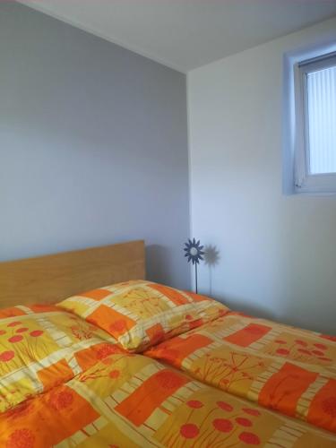 ein Schlafzimmer mit einem Bett mit einer gelben und orangefarbenen Decke in der Unterkunft Apartment Am Mühlenbusch in Neuss