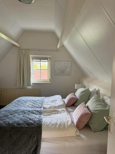 a bedroom with a bed with pillows and a window at Bed&Breakfast hotel de Greune Weide in Eibergen