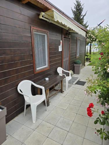 two white chairs and a bench on the side of a house at Dedin Konak in Golubac