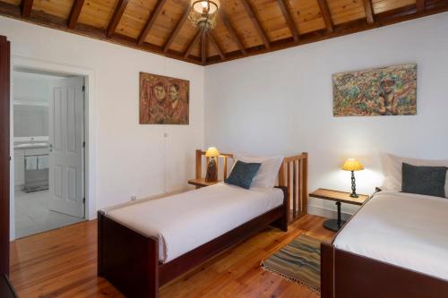 a bedroom with two beds and a door to a bathroom at Quinta da Fonte by An Island Apart in Calheta