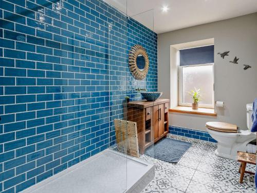 a blue tiled bathroom with a toilet and a window at 3 Bed in Lanark 81079 in Forth
