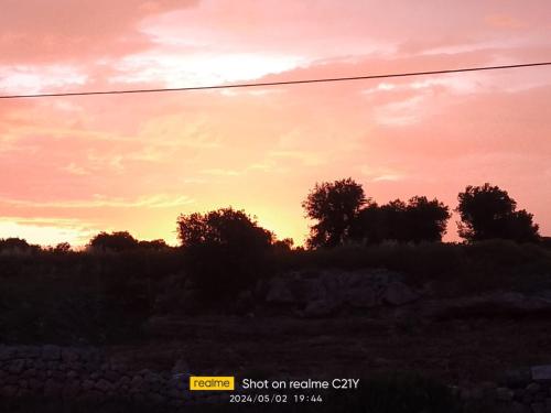 a sunset in a field with trees in the background at Masseria Ricci in Fasano