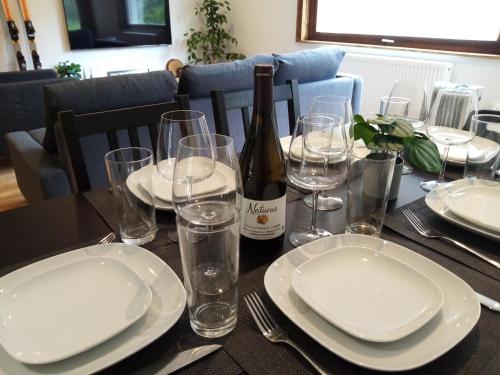 - une table avec des assiettes, des verres et une bouteille de vin dans l'établissement Appartement de Luxe avec Jacuzzi, Vue Montagne et Jardin, à Chamonix-Mont-Blanc