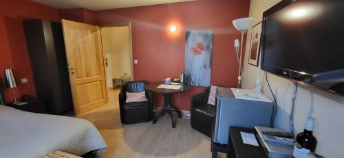 a room with a bed and a table and a television at B&B Herberg Boerenhol DE MOTE BVBA in Poperinge