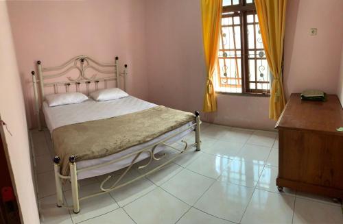 ein Schlafzimmer mit einem Bett, einer Kommode und einem Fenster in der Unterkunft Garuda Homestay in Bukittinggi