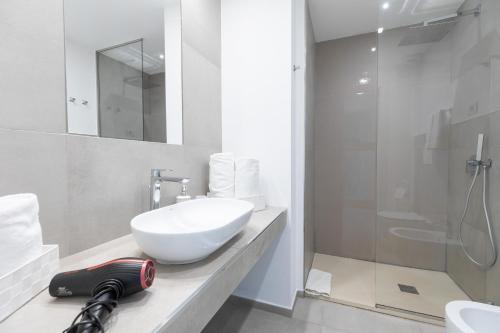 a bathroom with a white sink and a shower at Antares Rooms and Suites in Olbia