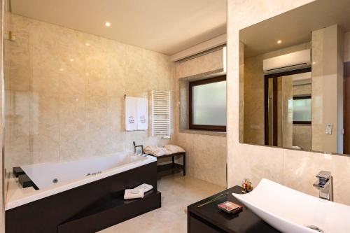 a bathroom with a tub and a sink and a mirror at Quinta de Cabanas Douro Country House in Penha Longa