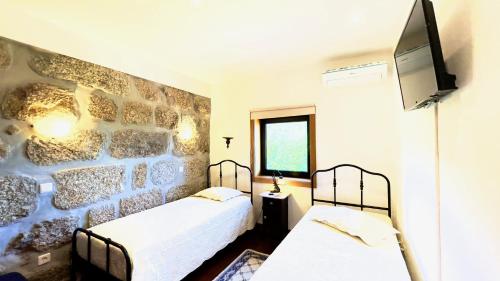 two beds in a room with a stone wall at Villa Amarela in Penafiel