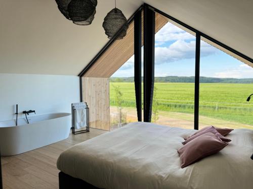Durbuy Insolite - Natural Escape في دربي: غرفة نوم بسرير كبير وحوض استحمام ونافذة كبيرة