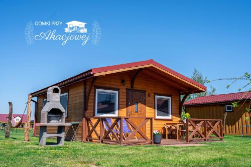 a log cabin with a porch and a large bell at Domki przy Akacjowej in Rydzewo